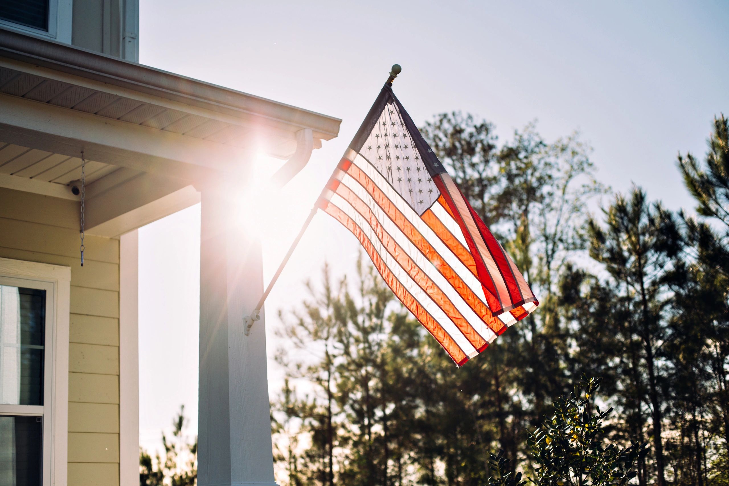 Patriotic house with the sun setting behind an American flag.