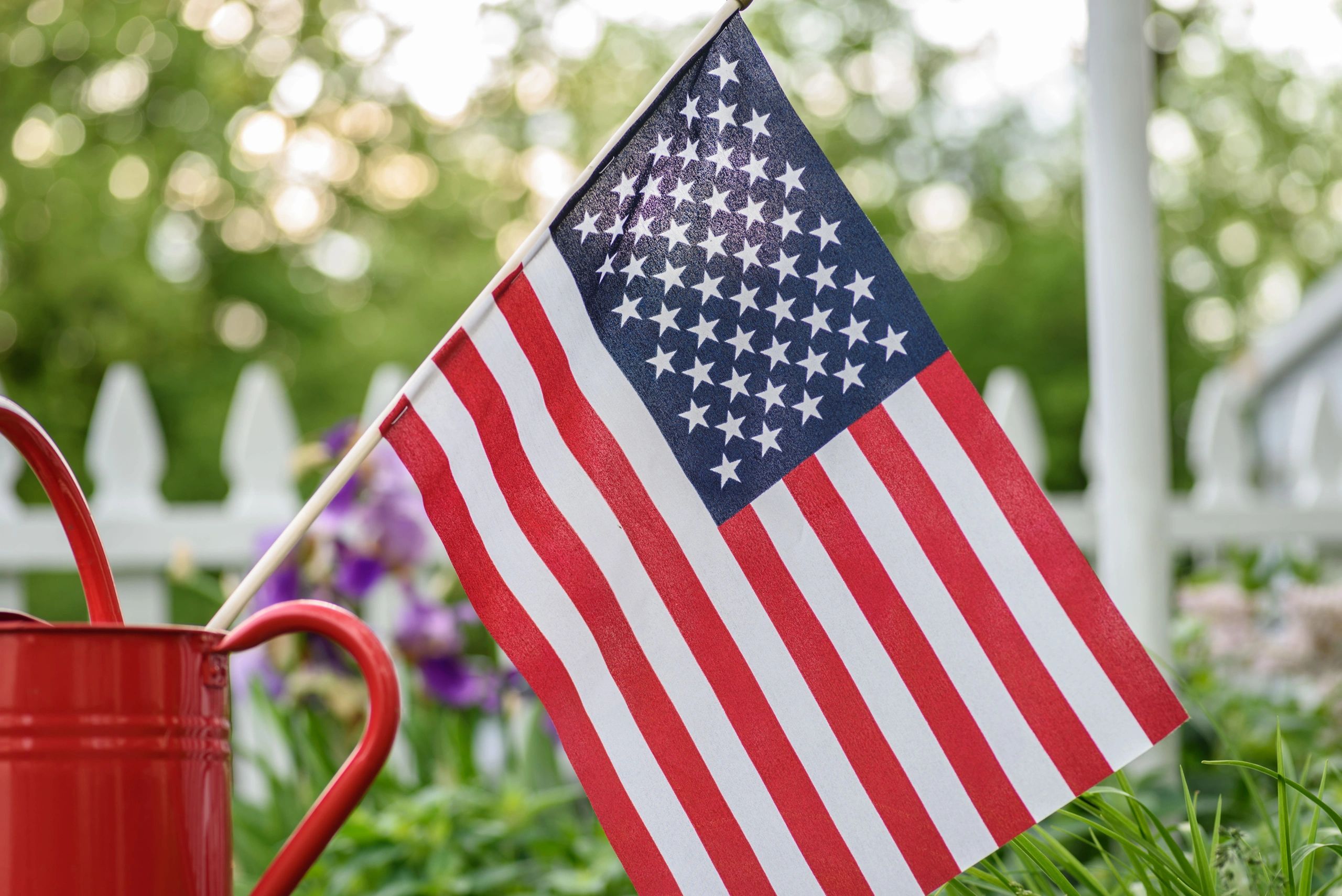 Red watering can holding an American flag.