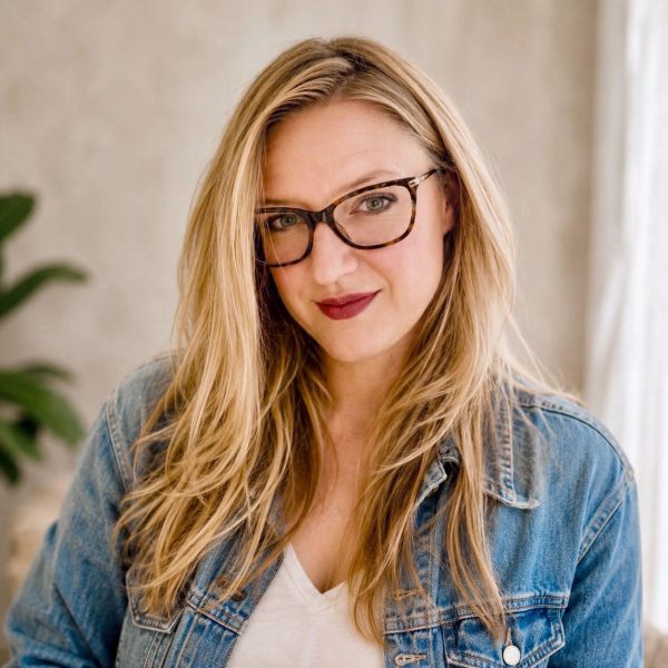 Smiling woman with glasses and long blonde hair.