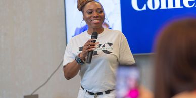 Woman speaking confidently at an event with a microphone.