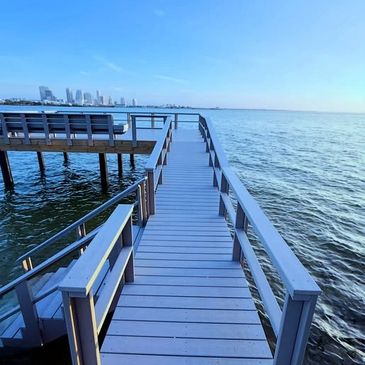Wooden pier extending into calm blue water under clear sky.