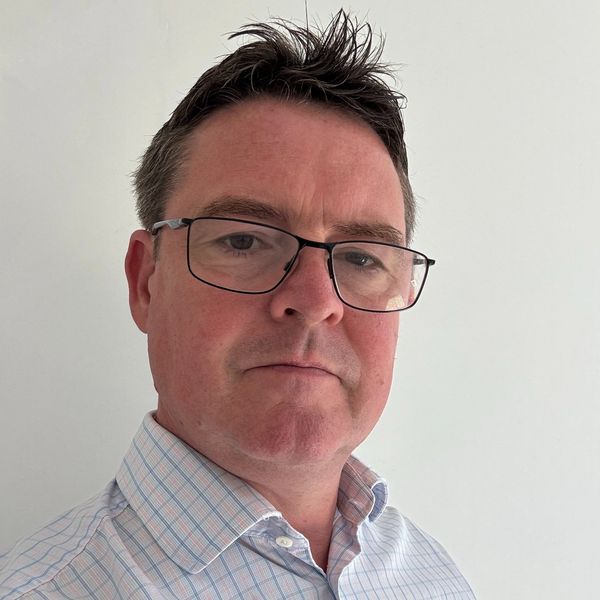 Man with glasses and spiked hair wearing a checkered shirt.