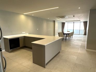 Modern open kitchen with dining area and large windows.
