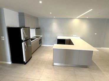 Modern kitchen with gray cabinets, stainless steel appliances, and an island counter.