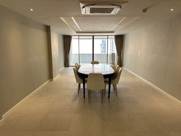 Minimalist dining room with a table and six chairs near large windows.