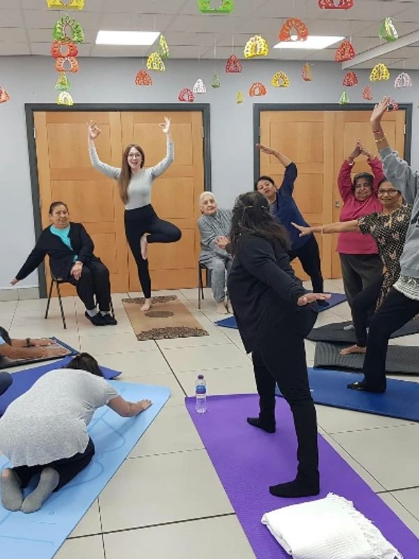 A group of people practicing yoga and stretching in a community room.