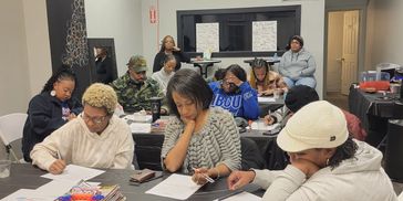 Group of people focused on paperwork in a classroom setting.