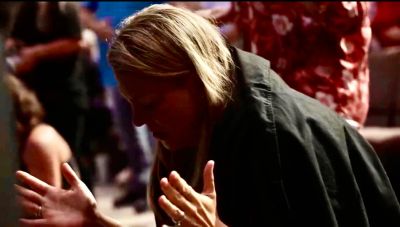 Person in deep thought or prayer with hands raised.