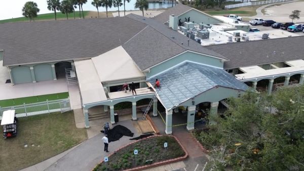 Workers constructing a glass roof on a large building.
