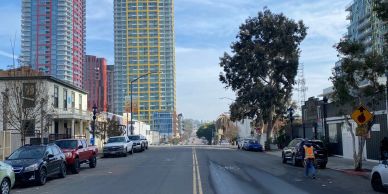 City street with tall buildings and parked cars.