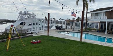 A backyard with pool, boat dock, and American flag under a cloudy sky.