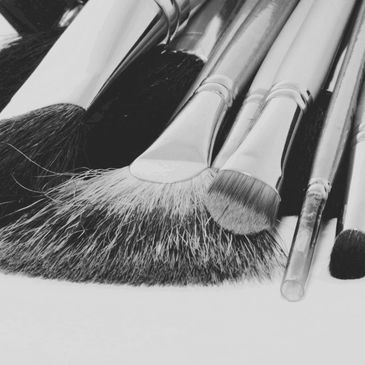 Black and white close-up of various makeup brushes.