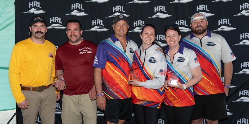 Group of six people posing with trophies in front of HRL backdrop.