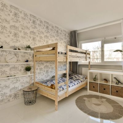 a kid's bedroom with a bunk bed, jungle them wallpaper and a lion floor rug. 