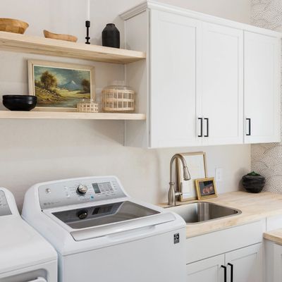 laundry room with a white washer, sink and white cabinets.