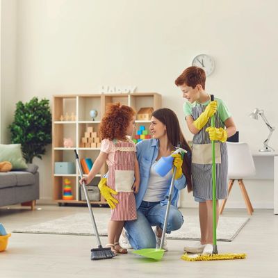 A family of three, mom, daughter and son with cleaning supplies ready to clean their living space. 