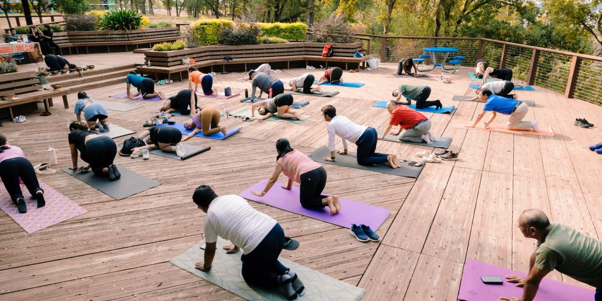Group yoga session in an outdoor wooden deck area.