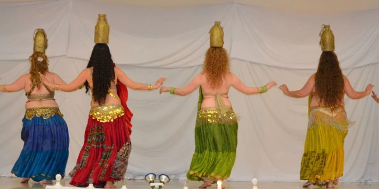 Four women dance with pots balanced on their heads.