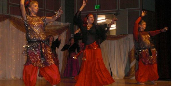 Three women performing traditional dance in colorful costumes.