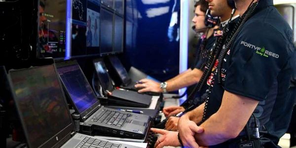 Race engineers monitor data on laptops during a motorsport event.