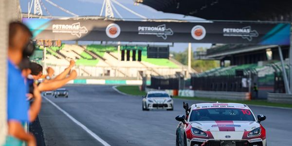 Race car number 10 celebrates victory on the track with cheering fans.