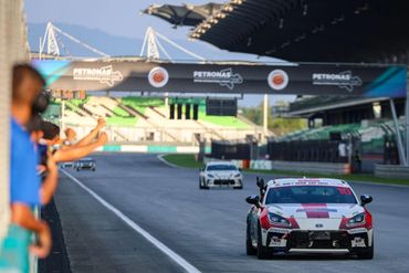 Race car number 10 celebrates victory on the track with cheering fans.