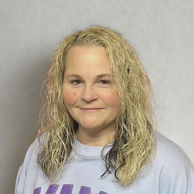 Smiling woman with curly blonde hair against a plain background.