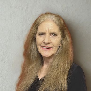 Smiling elderly woman with long hair against a plain background.