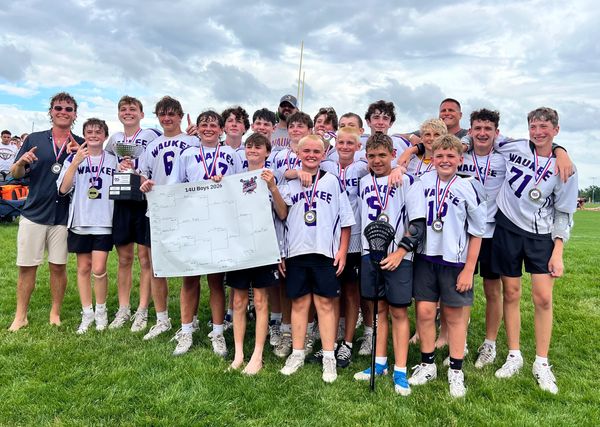 Youth team posing with medals on a sunny day.