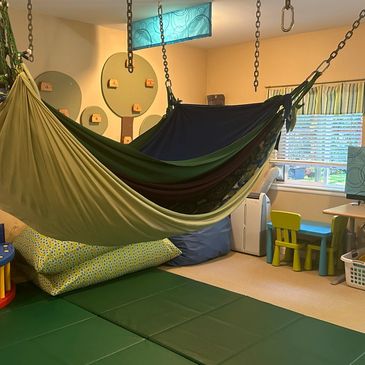 Stretchy multi-layer lycra hammocks hang over green mats.