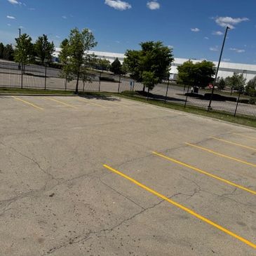 Empty parking lot with yellow lines under a blue sky.