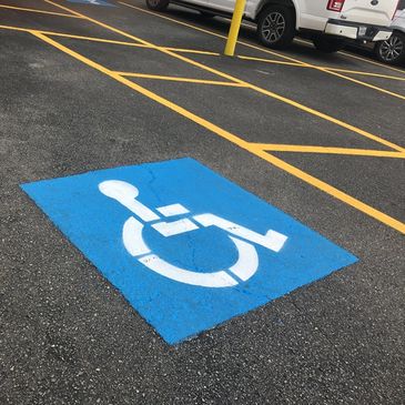 Blue handicapped parking symbol painted on asphalt in parking lot.
