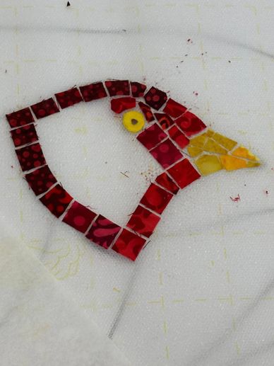 Colorful mosaic art forming a bird's head on a white background.