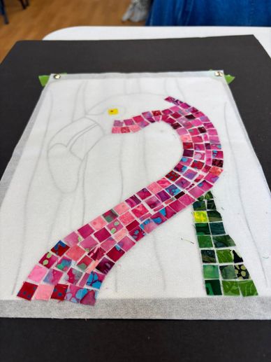 Colorful mosaic artwork of a flamingo in progress on fabric.