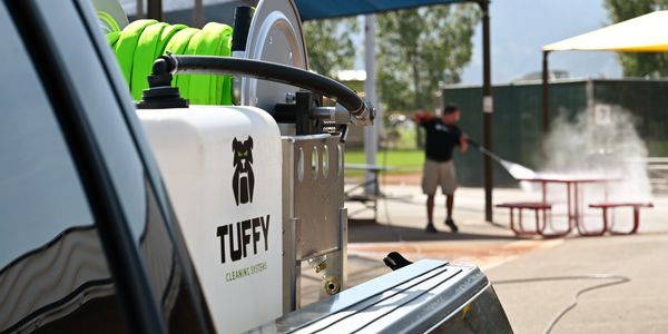 Photo of someone using the Tuffy Power Washer on park equipment.