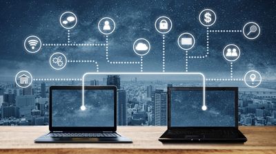 Two laptops connected by icons representing cloud computing and digital communication.