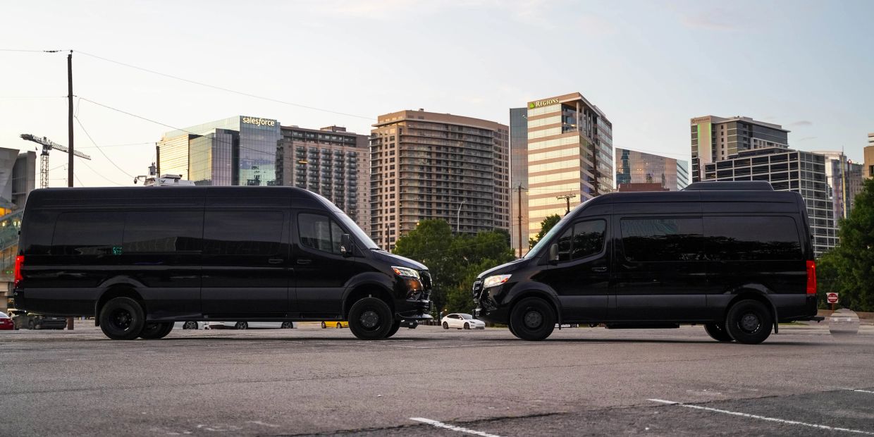 Two black vans facing each other against a city skyline.