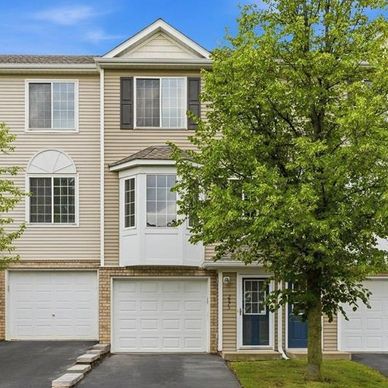 Three-story townhouse with garage and tree.