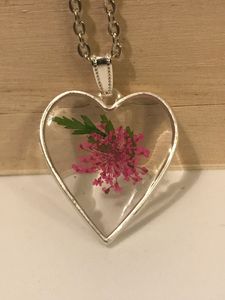 Silver coloured heart shaped necklace pendant with pink pressed dried flower incased in resin.