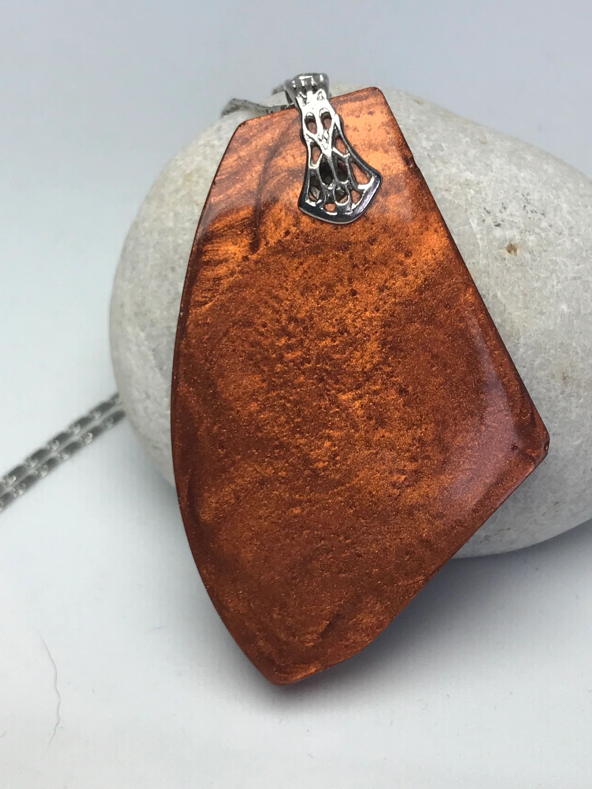Coper coloured resin pendant with silver necklace bail. Pendant is resin on a stone.