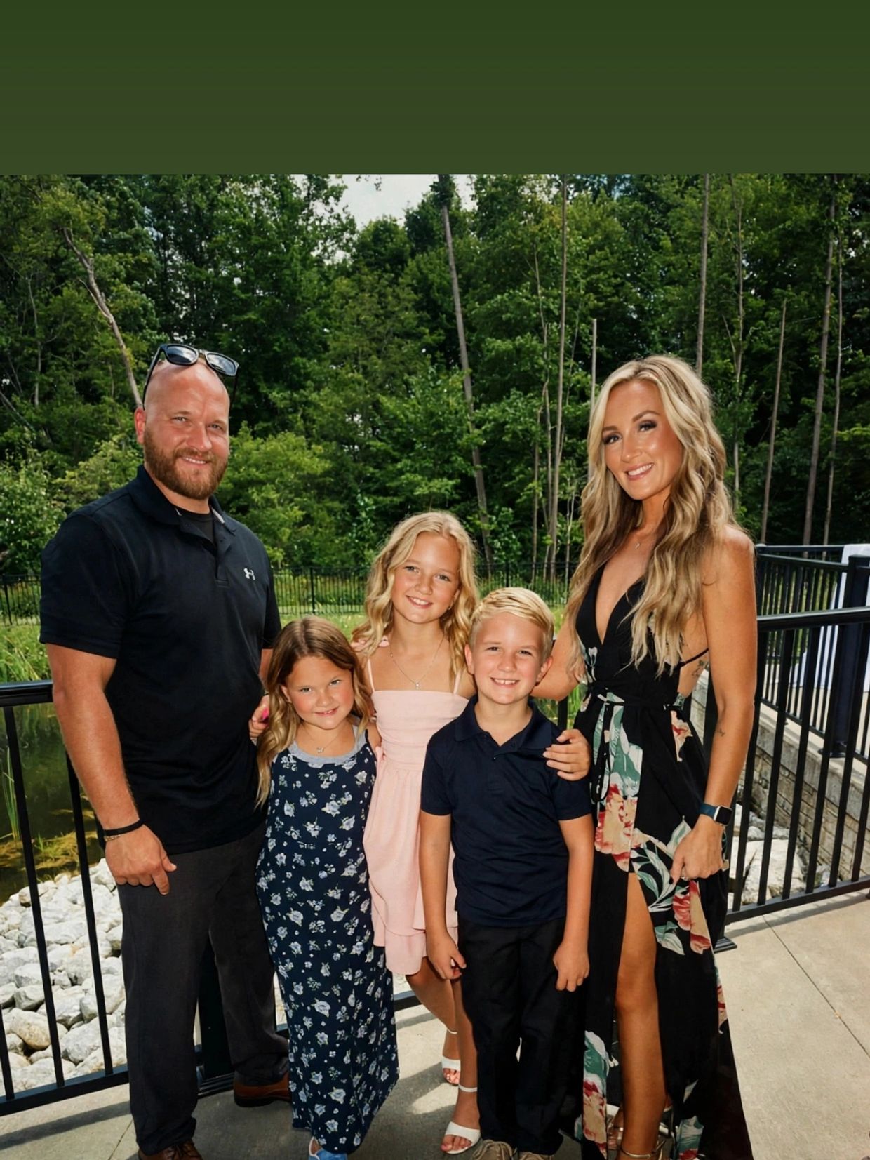 Happy family posing outdoors with greenery in the background.