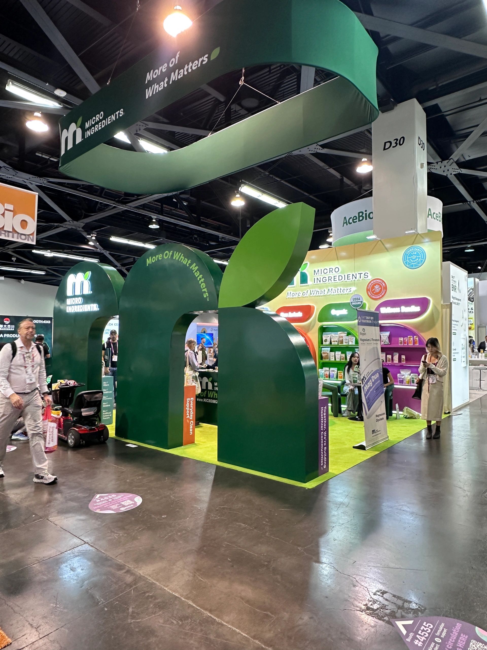 Trade show booth for Micro Ingredients with green leaf design and product displays.