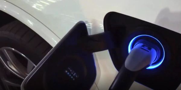 Electric car charging with glowing blue port light.