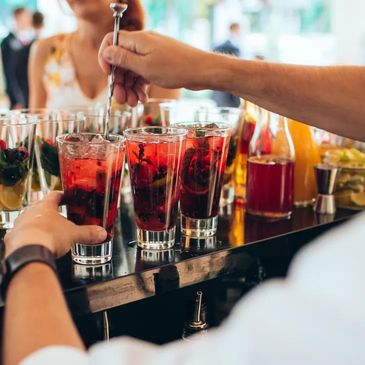 Bartender making red cocktails with fruits.