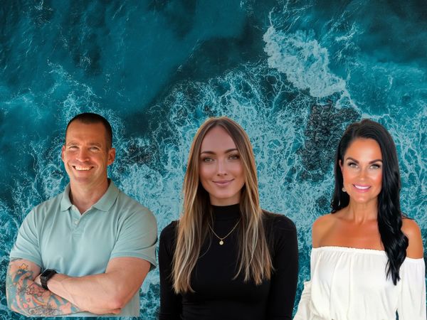 Three smiling people posing against a vibrant ocean wave background.