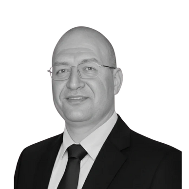 Portrait of a bald man wearing glasses and a suit with a tie.