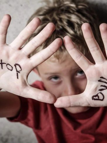 Child showing hands with 'Stop Bully' written, advocating against bullying.