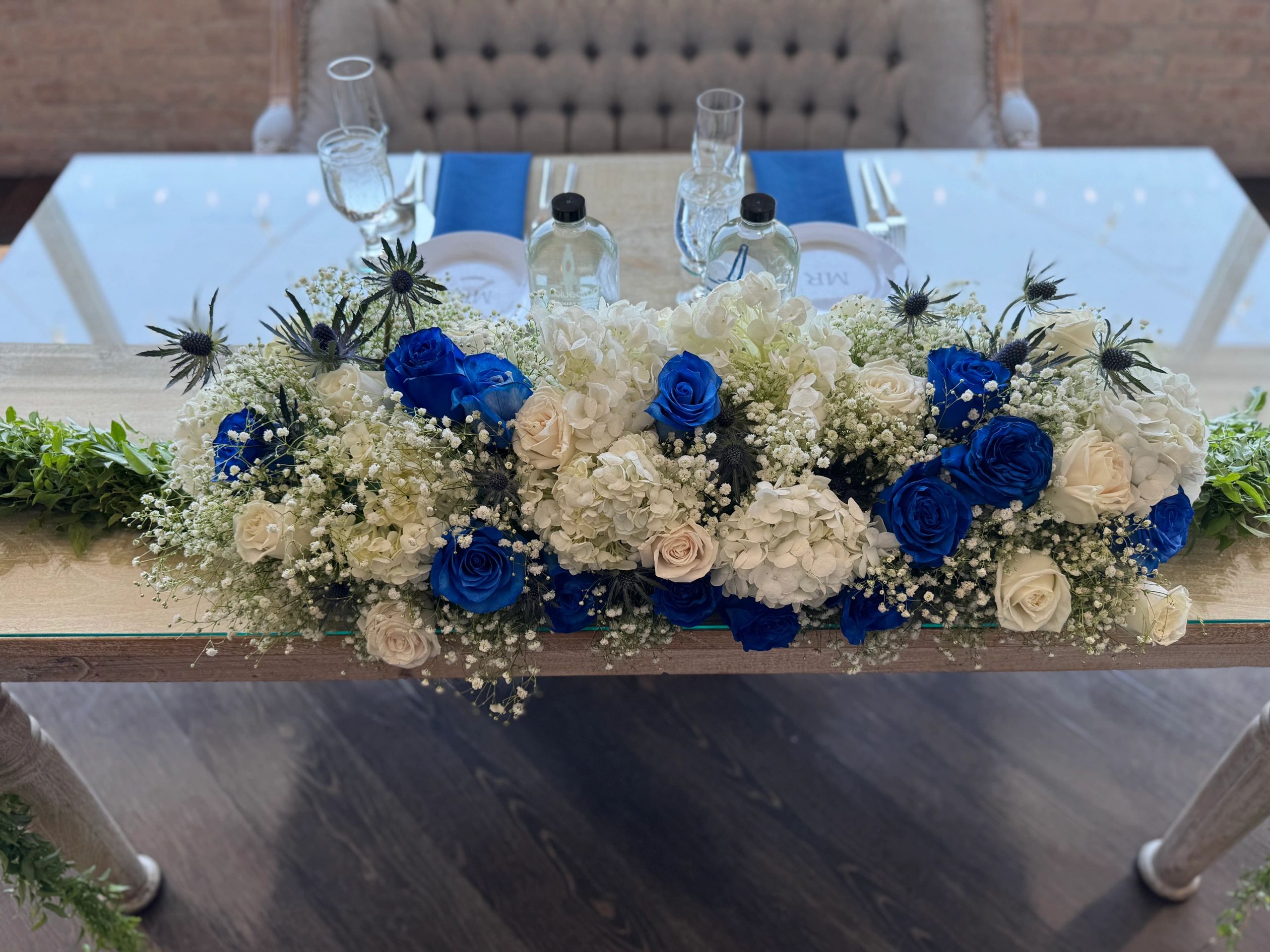 Wedding sweetheart  arrangement consisting of greenery, blue and white roses, and white hydrangeas 