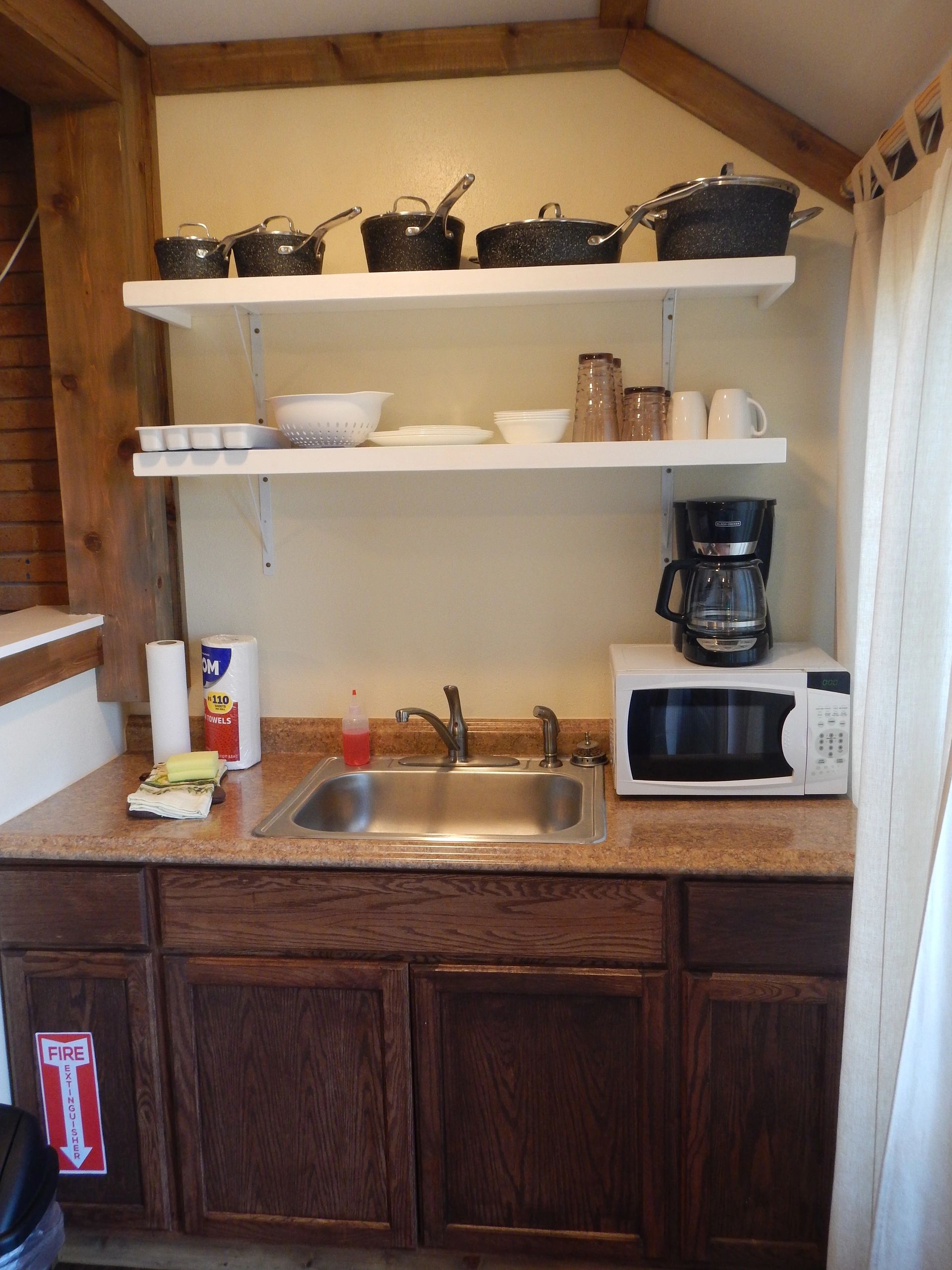 A small kitchenette with a sink, microwave, coffee maker, and cabinets.