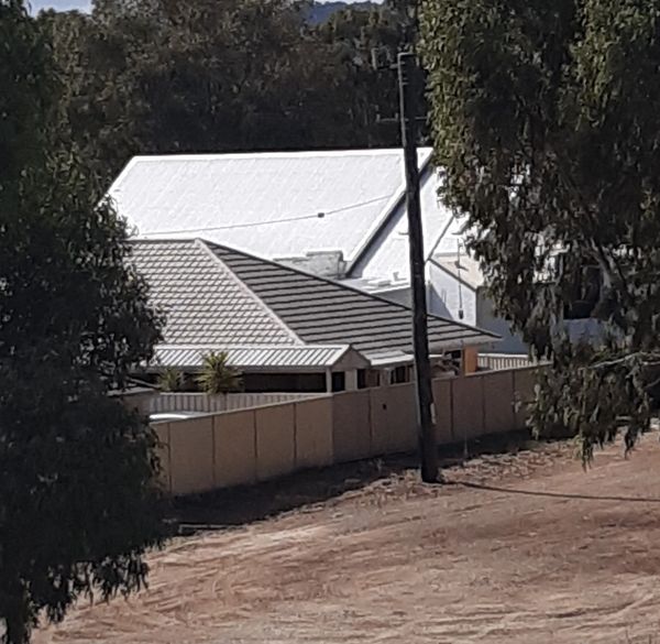 Residential rooftops and a fence surrounded by trees.